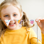 Girl in yellow shirt holding a string of small, colorful triangular flags with baking-themed designs.