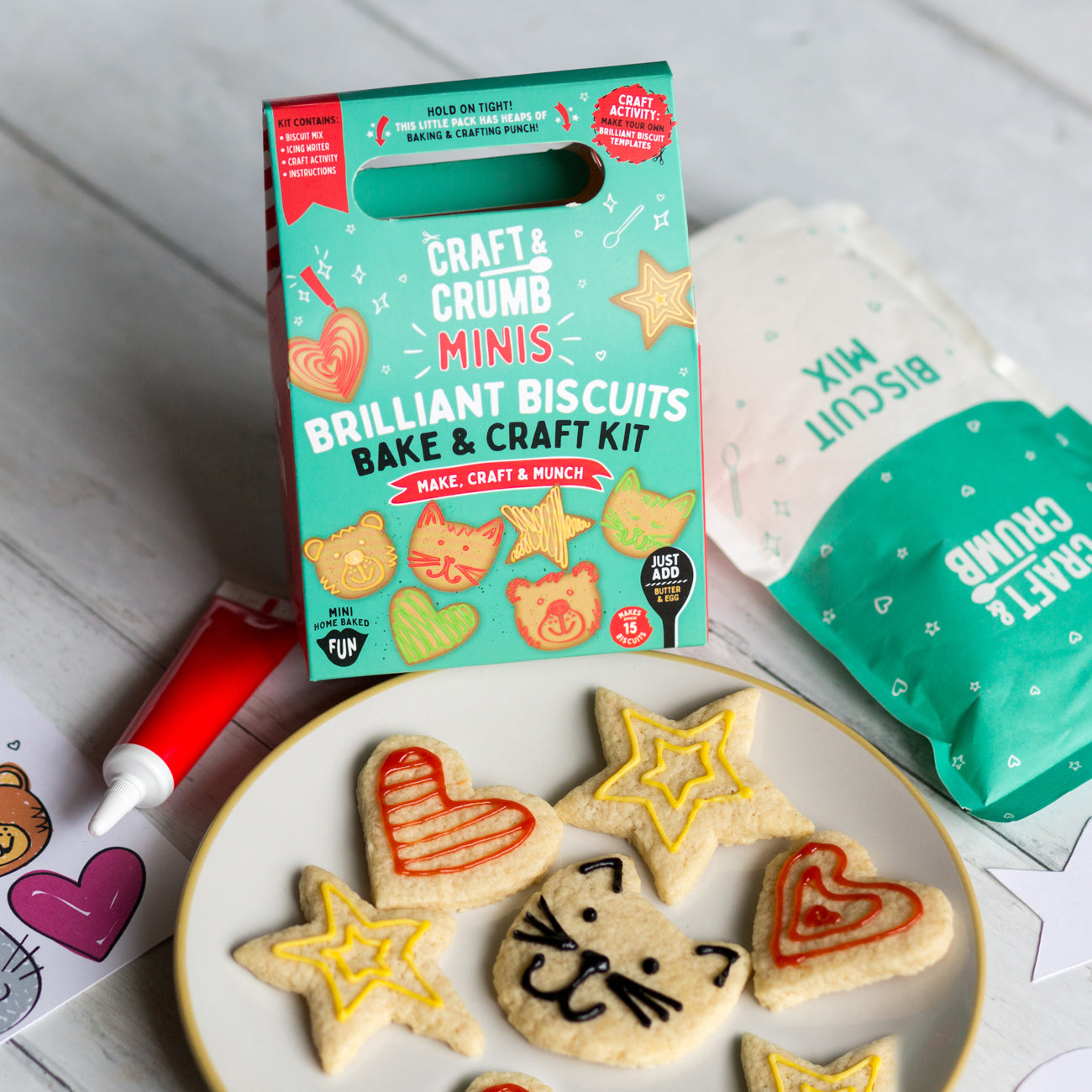 Cookie decorating kit with heart and star-shaped cookies, icing tube, and packaging on a wooden table.