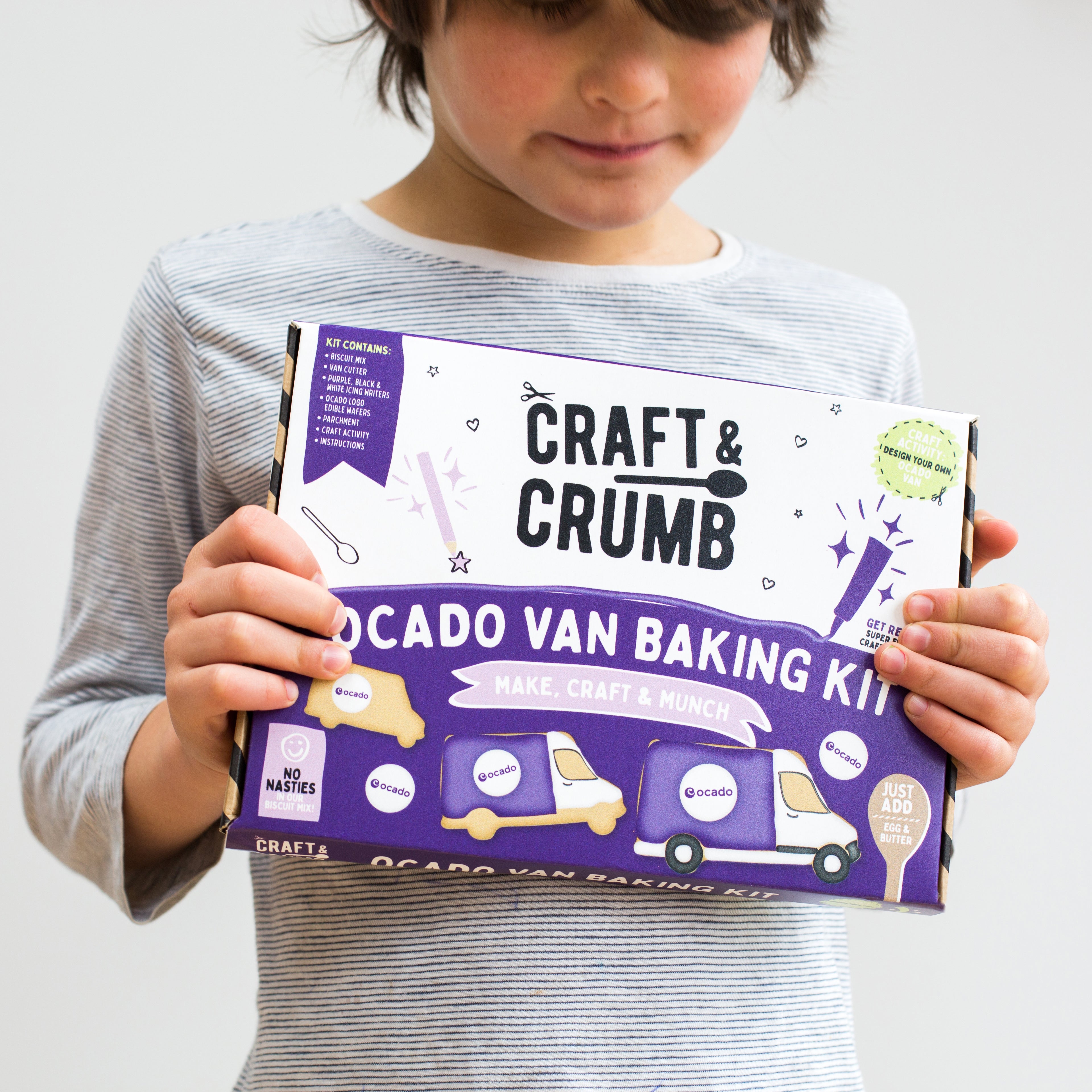 Child holding Craft & Crumb Ocado Van Baking Kit box, featuring a purple design with baking ingredients and instructions, ideal for kids' baking activities in the UK.