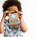 Child holding a party pancake kit box, wearing a dinosaur shirt, against a white background.