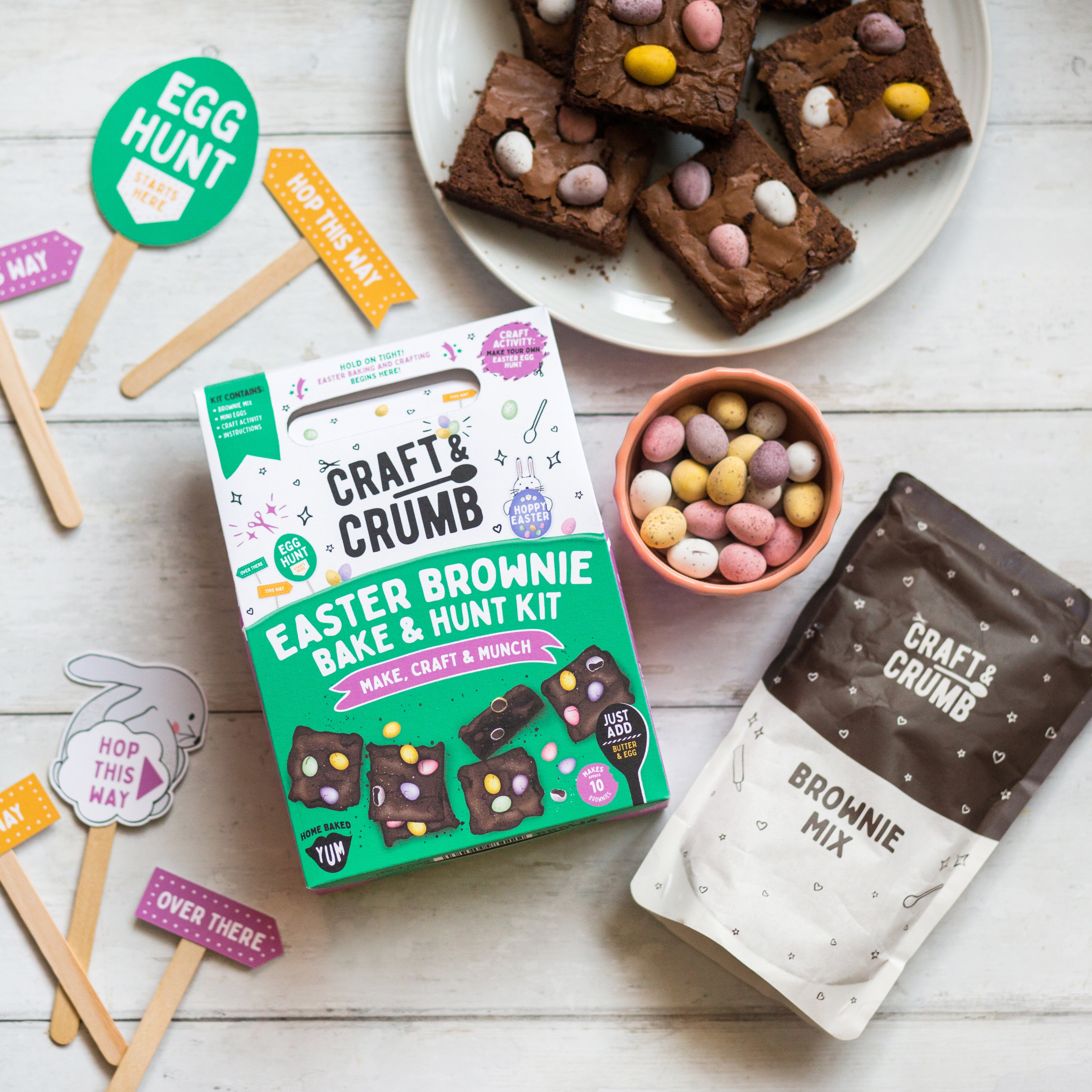 Easter brownie kit with mix, decorated brownies, mini eggs, and festive props on a white surface.