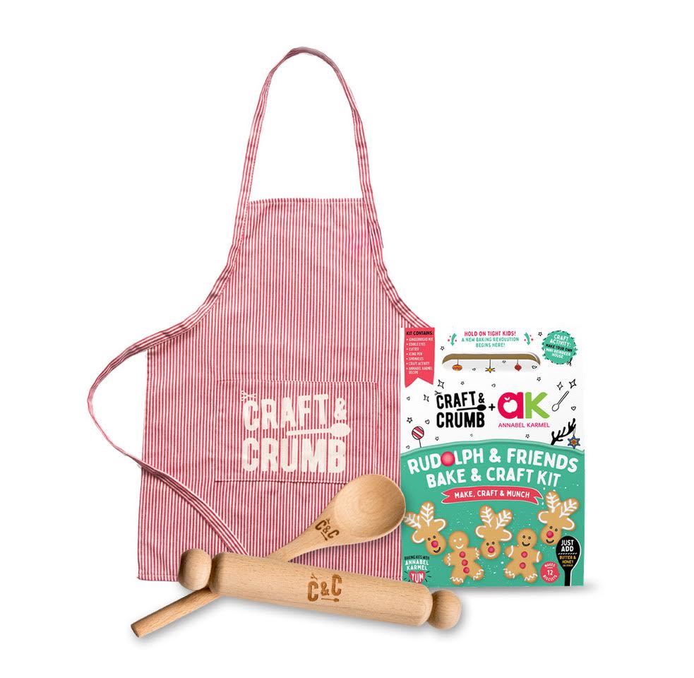 Red striped apron, wooden rolling pin, spoon, and Rudolph & Friends Bake & Craft Kit with gingerbread designs.
