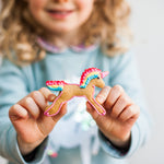 Child holding a unicorn-shaped cookie with colorful icing details.