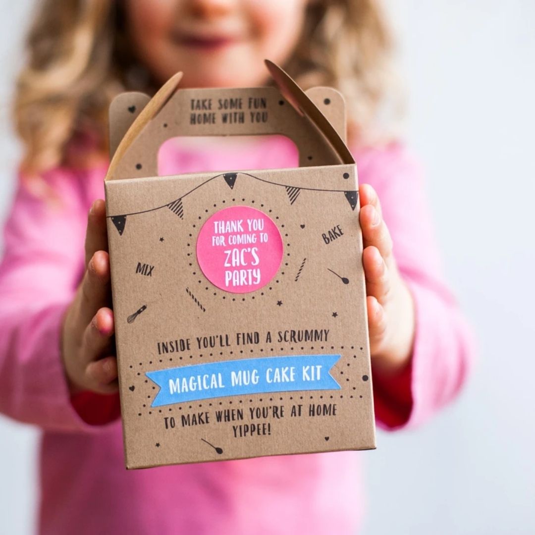 Child holding a Craft & Crumb Magical Mug Cake Kit party bag with "Thank You for Coming to Zac's Party" message.