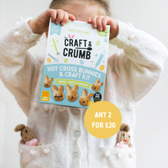 Child holding Craft & Crumb Hot Cross Bunnies & Craft Kit box, wearing a sweater with bunny pockets.