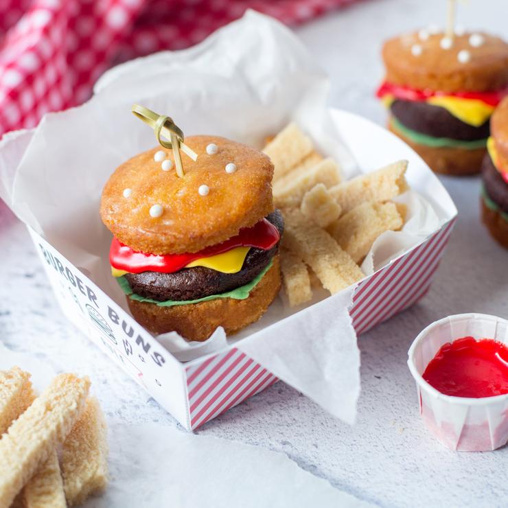 Cupcake burger with colorful icing resembling a cheeseburger, served in a striped box with biscuit fries, from Craft & Crumb's kids baking kit.