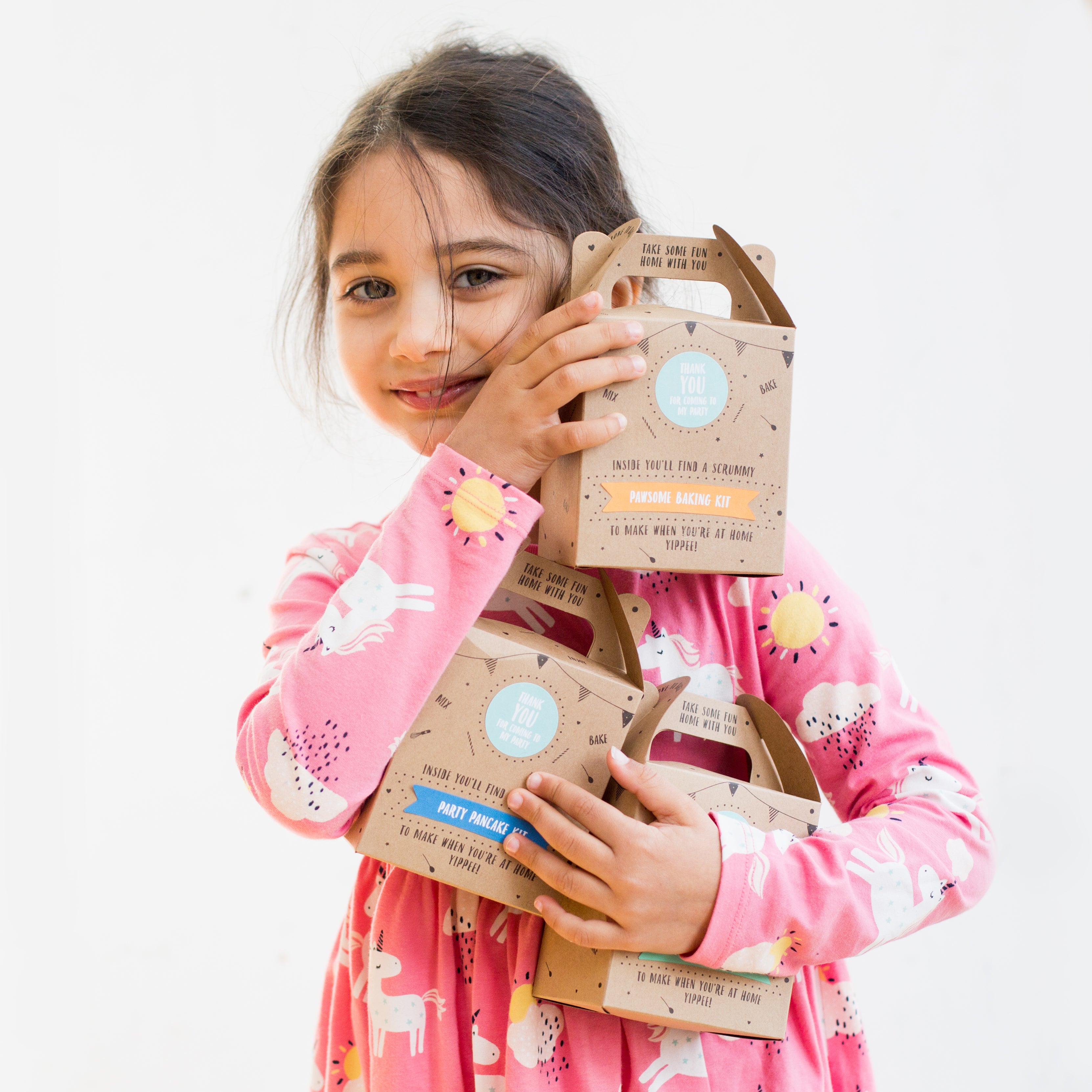 Girl holding party favor boxes from Craft & Crumb in front of white background