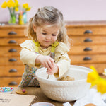 Young girl mixing dough in a large bowl, surrounded by baking ingredients on a wooden table.