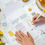 Person assembling a paper Easter bunny basket with instructions, using a yellow marker.