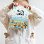 Child holding Craft & Crumb Hot Cross Bunnies & Craft Kit box, wearing a white sweater with bunny pockets.